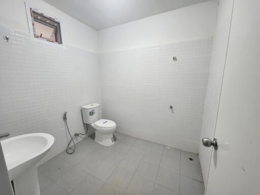 White tiled bathroom with toilet and sink