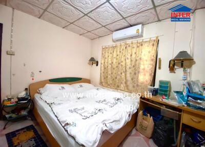 Bedroom with double bed, window air conditioning unit, and various personal items
