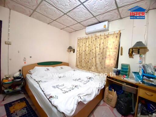 Bedroom with double bed, window air conditioning unit, and various personal items