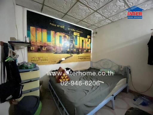 Bedroom with a bed, dresser, and a movie poster on the wall