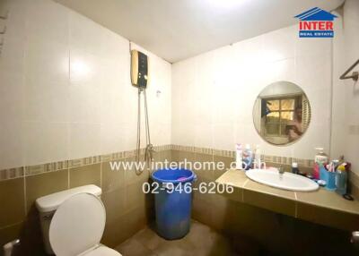 Bathroom with toilet, sink, round mirror, and electric water heater