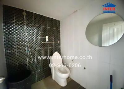 Bathroom with toilet, wall-mounted shower, and round mirror