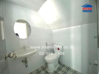 Bathroom with round mirror, sink, and toilet