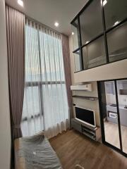 High ceiling living area with floor-to-ceiling windows and loft