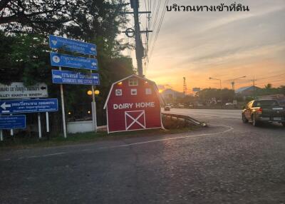 Photo of a road intersection with directional signs and a small red building labeled 