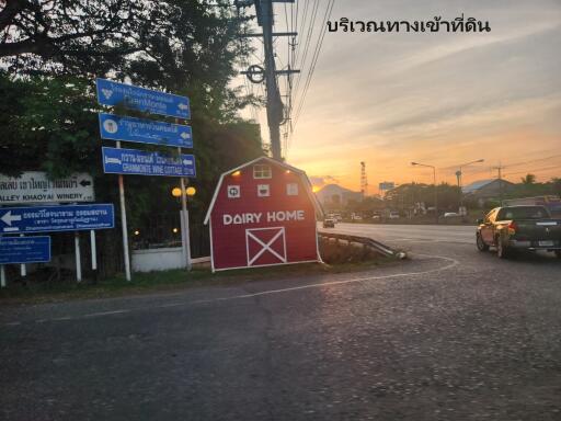 Photo of a road intersection with directional signs and a small red building labeled 