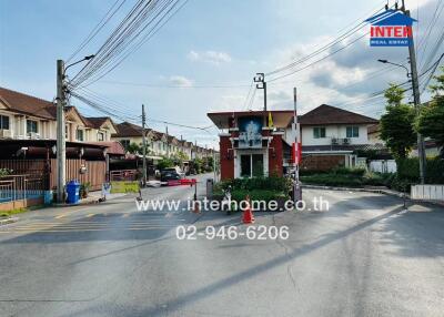 Gated residential community entrance with surrounding houses in the background