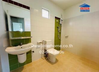 Modern bathroom with green accent tiles, white sink, and toilet