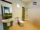 Modern bathroom with green accent tiles, white sink, and toilet