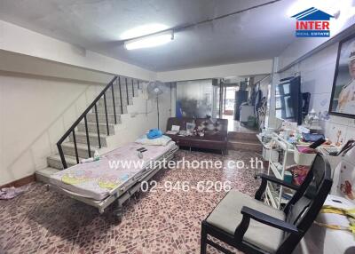 Main living area with tiled floor, sofa, bed, and staircase