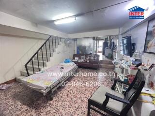 Main living area with tiled floor, sofa, bed, and staircase