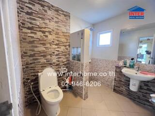 A clean and modern bathroom with a toilet, sink, mirror, and shower area.