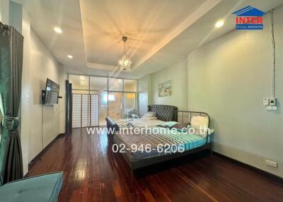 Spacious bedroom with wooden flooring, modern lighting, and a mounted TV