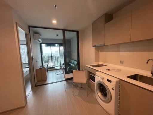 Open-plan kitchen and living area with washing machine and large windows