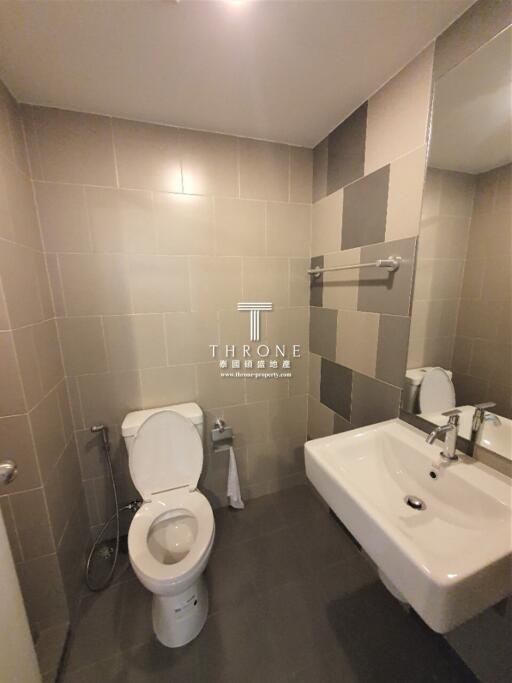 Modern bathroom with toilet, sink, and tiled walls