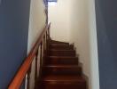 Wooden staircase with railing in a narrow hallway