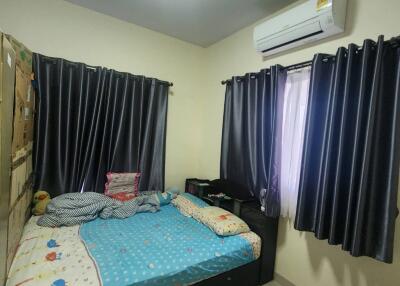 A cozy bedroom with air conditioning, dark curtains, and a bed with colorful bedding
