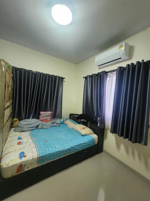 A cozy bedroom with air conditioning, dark curtains, and a bed with colorful bedding