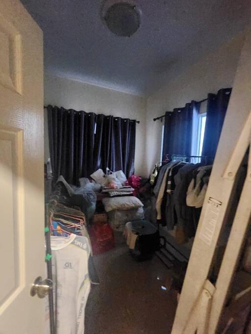 Cluttered bedroom with dark curtains and various personal items