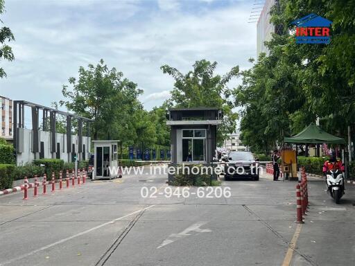 Gated entrance with security booths and surrounding greenery