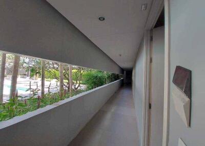 A corridor with a view of an outdoor garden and pool area