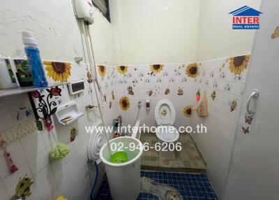 Bathroom with white tiles, sunflower decorations, toilet, sink, and shower