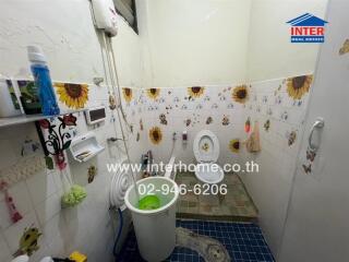 Bathroom with white tiles, sunflower decorations, toilet, sink, and shower