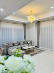 Elegant living room with large windows, gray sectional sofa, and chandelier