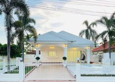 A beautiful white single-story house with a tiled roof and a well-maintained garden