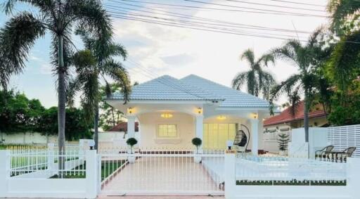 A beautiful white single-story house with a tiled roof and a well-maintained garden