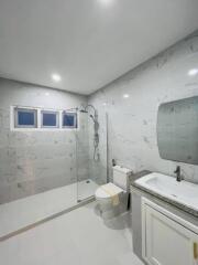 Modern bathroom with marble tiles, glass-enclosed shower, toilet, and vanity