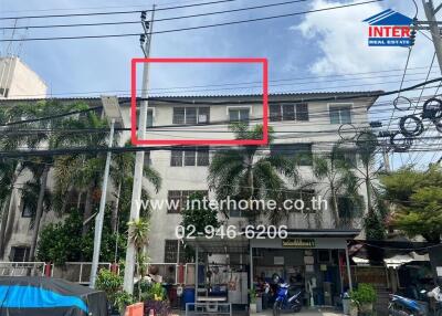 Three-story building with palm trees and power lines, featuring a commercial retail space on the ground floor.