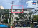 Three-story building with palm trees and power lines, featuring a commercial retail space on the ground floor.