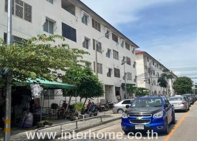 Four-story residential building with parked cars in front