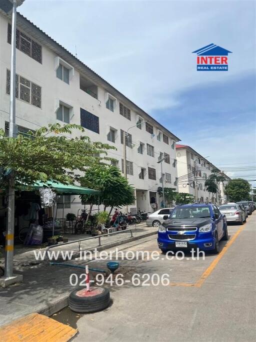 Four-story residential building with parked cars in front