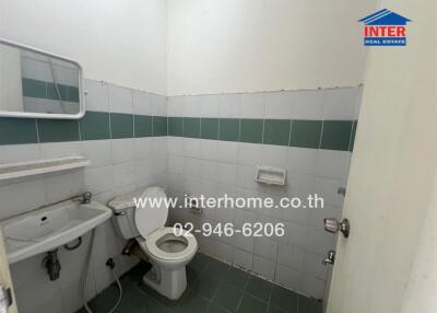 Bathroom with toilet, sink, and tiled walls