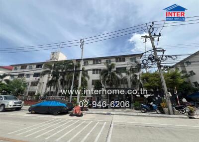 Street view of a multi-story residential building with a palm tree lined street