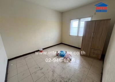 Empty bedroom with wardrobe, windows, and tiled floor.