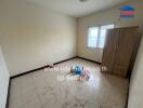 Empty bedroom with wardrobe, windows, and tiled floor.