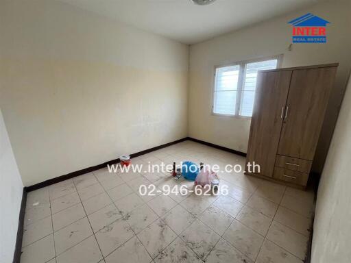 Empty bedroom with wardrobe, windows, and tiled floor.