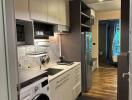 Modern kitchen with appliances and wooden flooring leading to living area