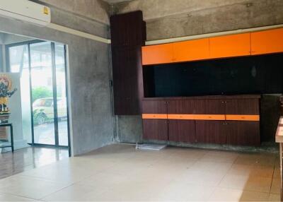 Spacious living room with built-in wooden cabinets and bright orange accents