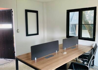 Office space with two desks and chairs, window, and entrance door