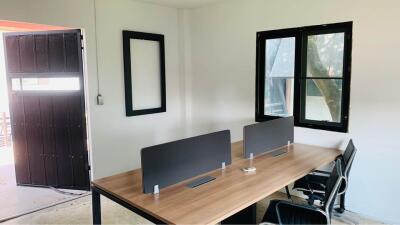 Office space with two desks and chairs, window, and entrance door