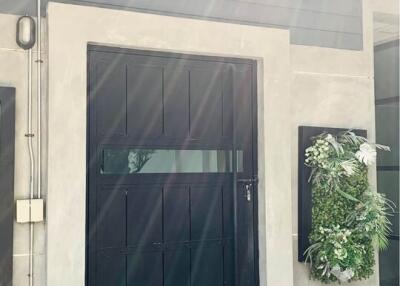 Front entrance of a modern building with a black door and a wall-mounted garden