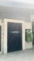 Front entrance of a modern building with a black door and a wall-mounted garden