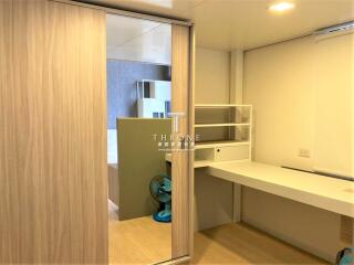 Well-lit modern bedroom with wooden sliding door, built-in shelves, and work desk.