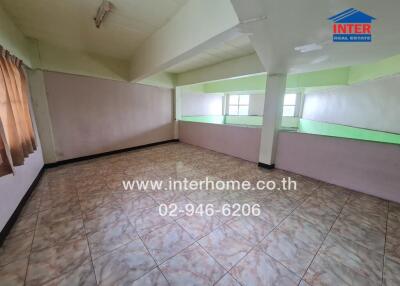 Spacious empty room with tiled flooring and large windows.
