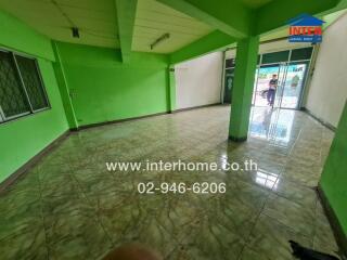 Spacious empty living area with tiled floors and green walls