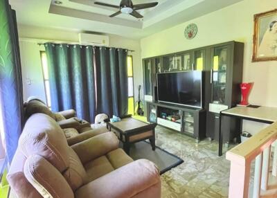 Living room with beige recliner chairs, large TV, ceiling fan, and natural light